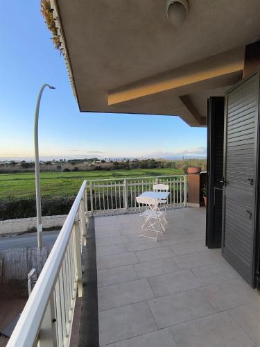 a balcony with a table and a view of a field at Appartamento d' amare vicino il mare in Marzamemi