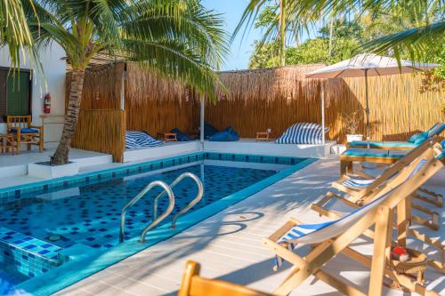 a swimming pool with two chairs and a palm tree at Lanta Secret House in Ko Lanta