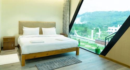 a bedroom with a bed and a large window at SkyGrove in Kodaikānāl