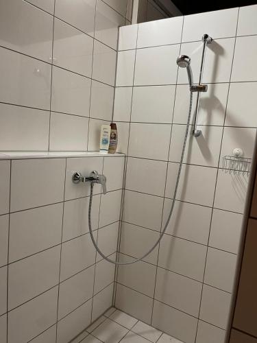 a shower with a hose in a white tiled bathroom at Romantischer Zirkuswagen in Edemissen