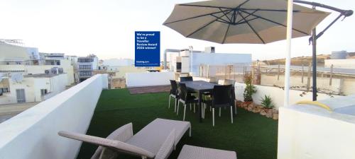 a balcony with a table and chairs and an umbrella at Charming Townhouse - Steps from Waterfront in Marsaxlokk