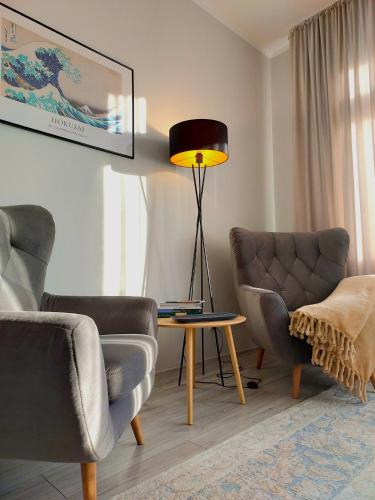 a living room with two chairs and a table and a lamp at Tullu Apartament - w centrum, blisko bulwaru, blisko molo in Ostróda