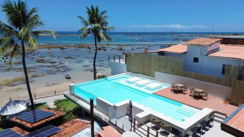 a house with a swimming pool next to a beach at Chez Max Pousada in Morro de São Paulo