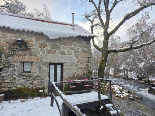 a stone house in the snow with a bench in front at Moinhos do Poço Verde in Castro Laboreiro