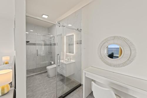 a white bathroom with a sink and a mirror at Lagun Ocean View Apartments & Studio in Lagun