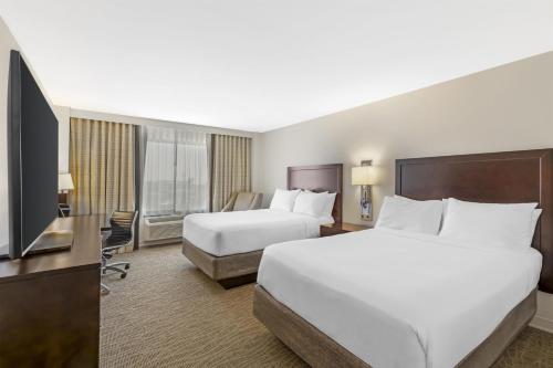 a hotel room with two beds and a flat screen tv at Sonesta Atlanta Airport North in Atlanta