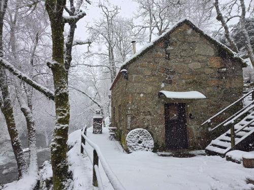a stone barn in the snow in a forest at Moinhos do Poço Verde in Castro Laboreiro