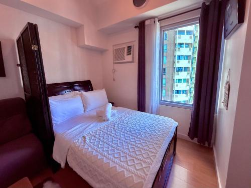 a small bedroom with a bed and a window at Cozy Condo in Ermita Manila near St Lukes Medical Center and US Embassy in Manila