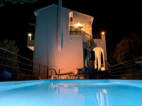 a large swimming pool in front of a building at night at Private villa Pyrgos - Heated Pool & Sea View - Walking distance from beaches & Liapades in Liapades