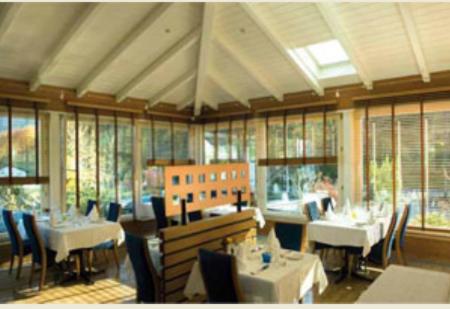 un restaurante con mesas y sillas blancas y ventanas en Hôtel de l'Etoile en Perrefitte