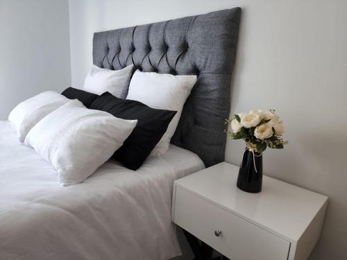 a bed with white pillows and a vase with flowers on a night stand at Casa The Jade in Cape Town