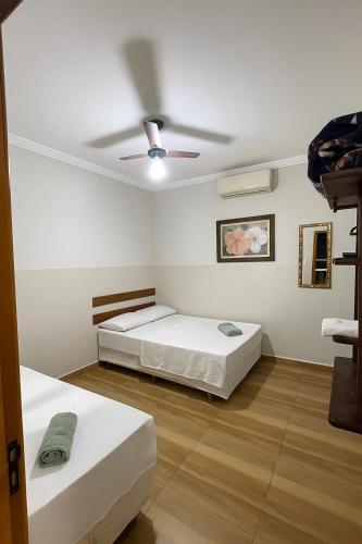 a bedroom with two beds and a ceiling fan at Hotel Pousada Dona Ana in Aparecida