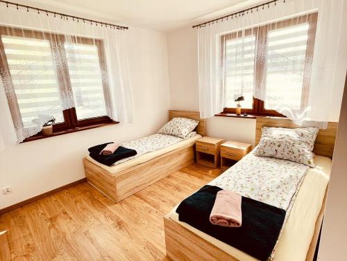 two beds in a room with two windows at APARTAMENT RYBICAL nad jeziorem in Ryn