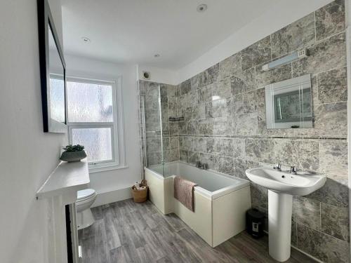 a bathroom with a sink and a toilet and a tub and a sink at Stylish 2-Bed Home with Garden in Saint Thomas Station