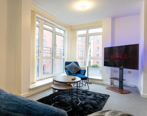 a living room with a tv and a chair and a table at The Beauchamp Modern 2BR Coventry City Centre Apt Free Parking in Coventry