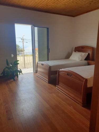 a bedroom with two beds and a sliding glass door at Farol Golfe in Ponta do Pargo