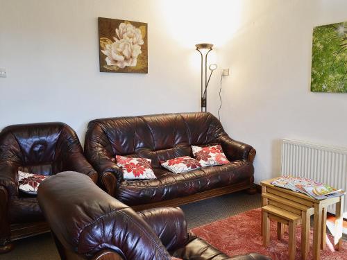 a living room with two leather couches and a table at Tanpencefn Mawr in Brynsiencyn