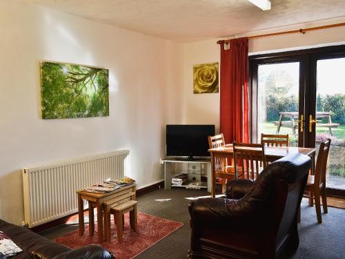 a living room with a couch and a table and a television at Tanpencefn Mawr in Brynsiencyn