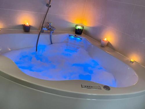 a bath tub filled with blue water with two candles at BERGERIE PLAGE 5 personnes Rénové avec climatisation et bain à remous in Hyères