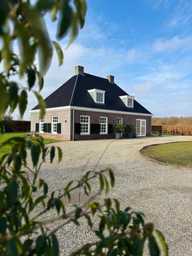 a large house with a black roof and a driveway at Het Koetshuis in Zwolle