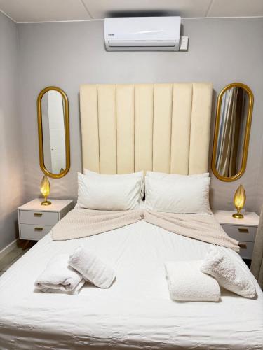 ein Schlafzimmer mit einem großen weißen Bett und zwei Spiegeln in der Unterkunft Elevare suites in Nelspruit