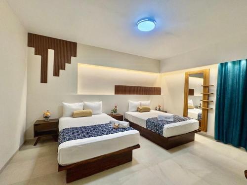 a hotel room with two beds and a mirror at Hotel Taxaha in Candelaria
