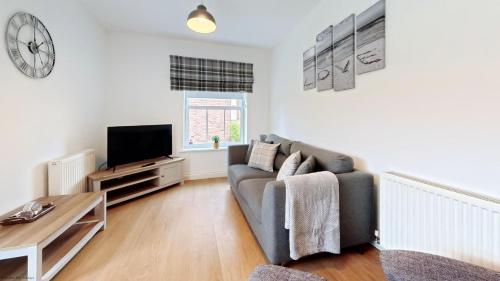 a living room with a couch and a tv at Bliss On The Bay - Part of the The Bay Filey Holiday Village with pool, gym and direct beach access, pub, restaurant, tennis and meadows walks in Filey