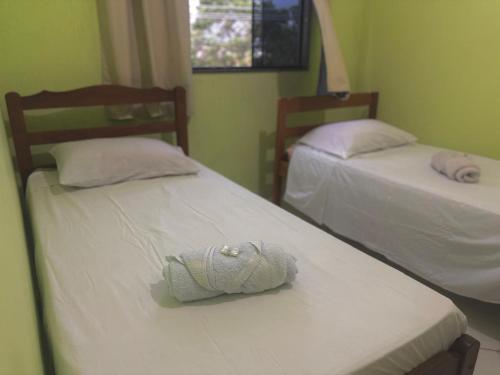 a room with two beds with a towel on them at Hostel Costa Rio in Rio das Ostras