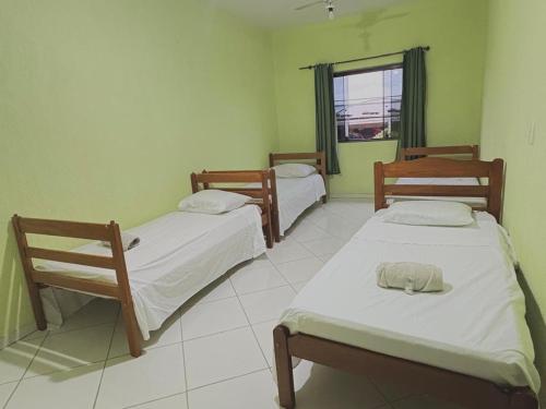 a room with three beds and a window at Hostel Costa Rio in Rio das Ostras