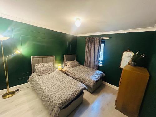 a bedroom with two beds and a green wall at Modern & cozy 2 bedroom flat in Dundee