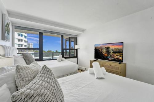 a bedroom with two beds and a flat screen tv at Large Ocean View 2 BDR Condo Beachfront Hotel 504 in Miami Beach