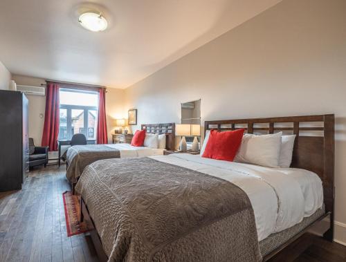 two beds in a hotel room with red pillows at Petit Hôtel - Café Krieghoff in Quebec City