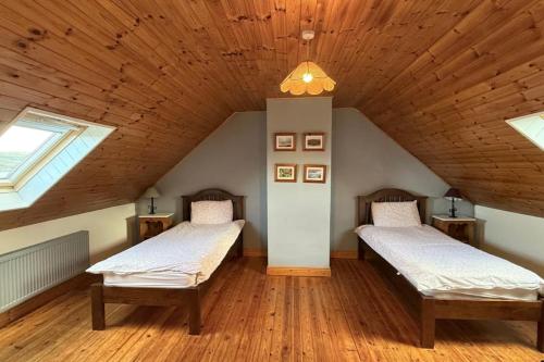 two beds in a room with a wooden ceiling at Skellig Cottage - Portmagee in Lateeve