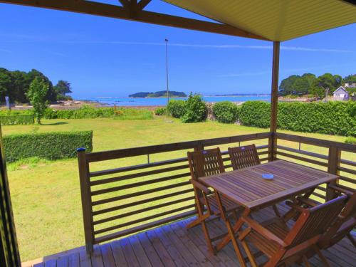 a wooden table and chairs on a deck with an umbrella at Camping de l'Espérance - Camping Côte de granit rose - Trébeurden - Ile grande - GR34 in Trébeurden
