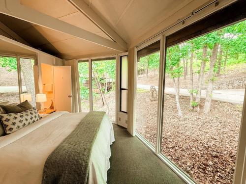a bedroom with a bed and large windows at 10 Branch Bungalow Treetop in Four Seasons