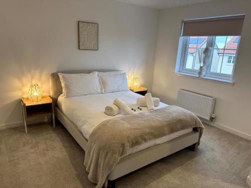 a bedroom with a bed with two lamps and a window at Luxury 4BR Detached Exec Home in Cadzow