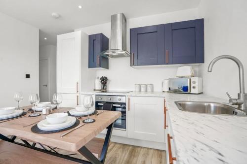 a kitchen with blue cabinets and a wooden table at City centre FREE Parking Families and Contractors Sleeps 5 with a view in Norwich