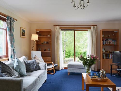 a living room with a couch and a tv at Bethany Cottage in Aberfoyle