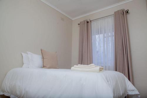 białe łóżko z białymi poduszkami i oknem w obiekcie BP property w mieście Harare