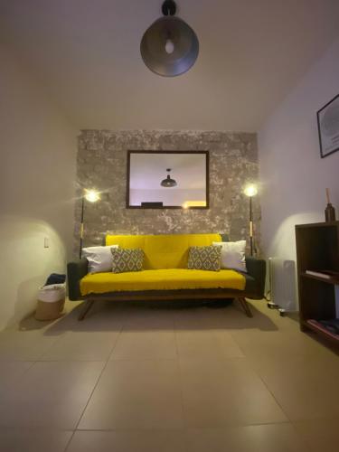 a yellow couch in a room with a brick wall at Cozy Flat Condesa in Mexico City