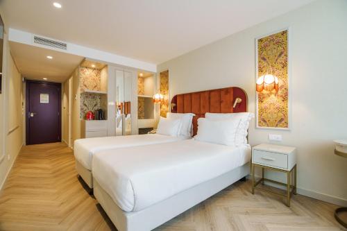 a bedroom with a large white bed and a bathroom at Olympia Lis Baixa Hotel in Lisbon