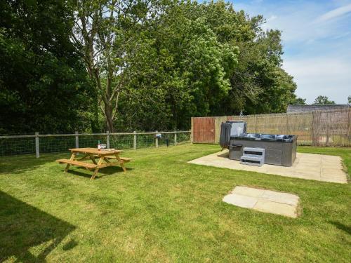 a picnic table and a grill in a yard at Bluebell - Shepherd Hut - Uk49948 in Oswestry