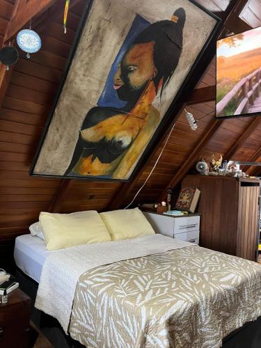 a bedroom with a bed and a painting on the wall at Canto Gira Sol - Estúdio Borboleta in Penha