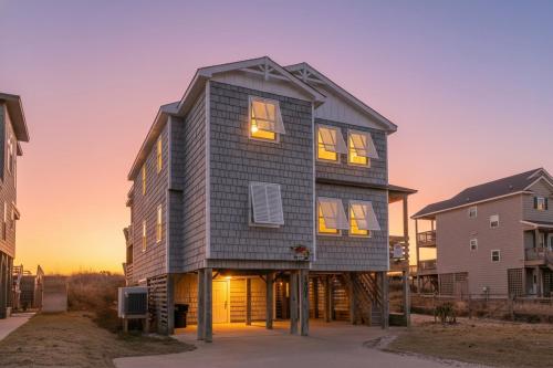 a large house is shown with the sunset in the background at T.L. Sea - KDH MP 6, Oceanfront, Ocean view, Rec Room, Spacious Decks, Private Walk to Beach in Kill Devil Hills