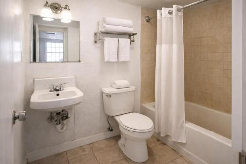 a white bathroom with a toilet and a sink at Siesta Motor Inn Kissimmee Near Disney World in Kissimmee