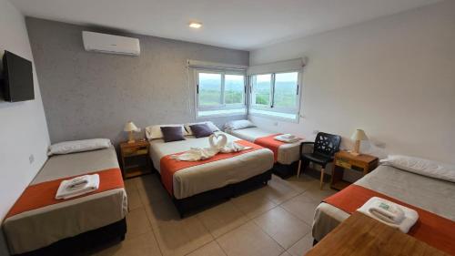 a hotel room with three beds and a window at Complejo Gran Chacha in Tanti