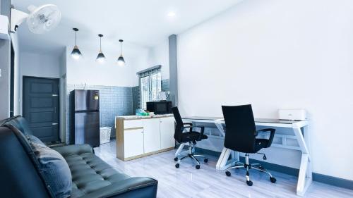 a living room with a couch and a desk and chairs at The Engineer's Villas, Krabi in Ban Khlong Chi Lat