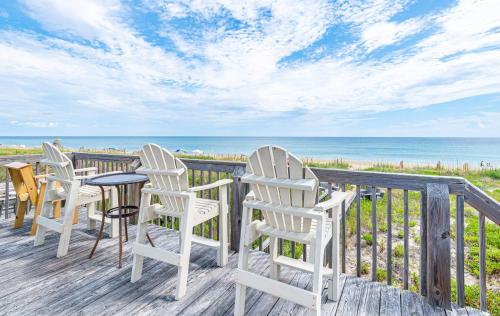 a porch with chairs and a table and the ocean at Serendipity - KDH MP 6.5, Oceanfront, Amazing Ocean View, Hot Tub, Pets OK, YR Flex Stays in Kill Devil Hills