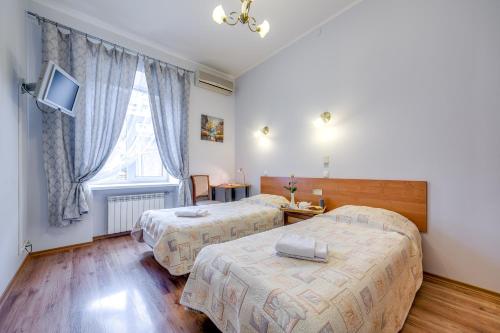 ein Hotelzimmer mit 2 Betten und einem Fenster in der Unterkunft Park Lane Inn in Sankt Petersburg