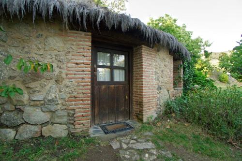 a brick building with a door and a grass roof at Casa Rural Arbillas in Arenas de San Pedro